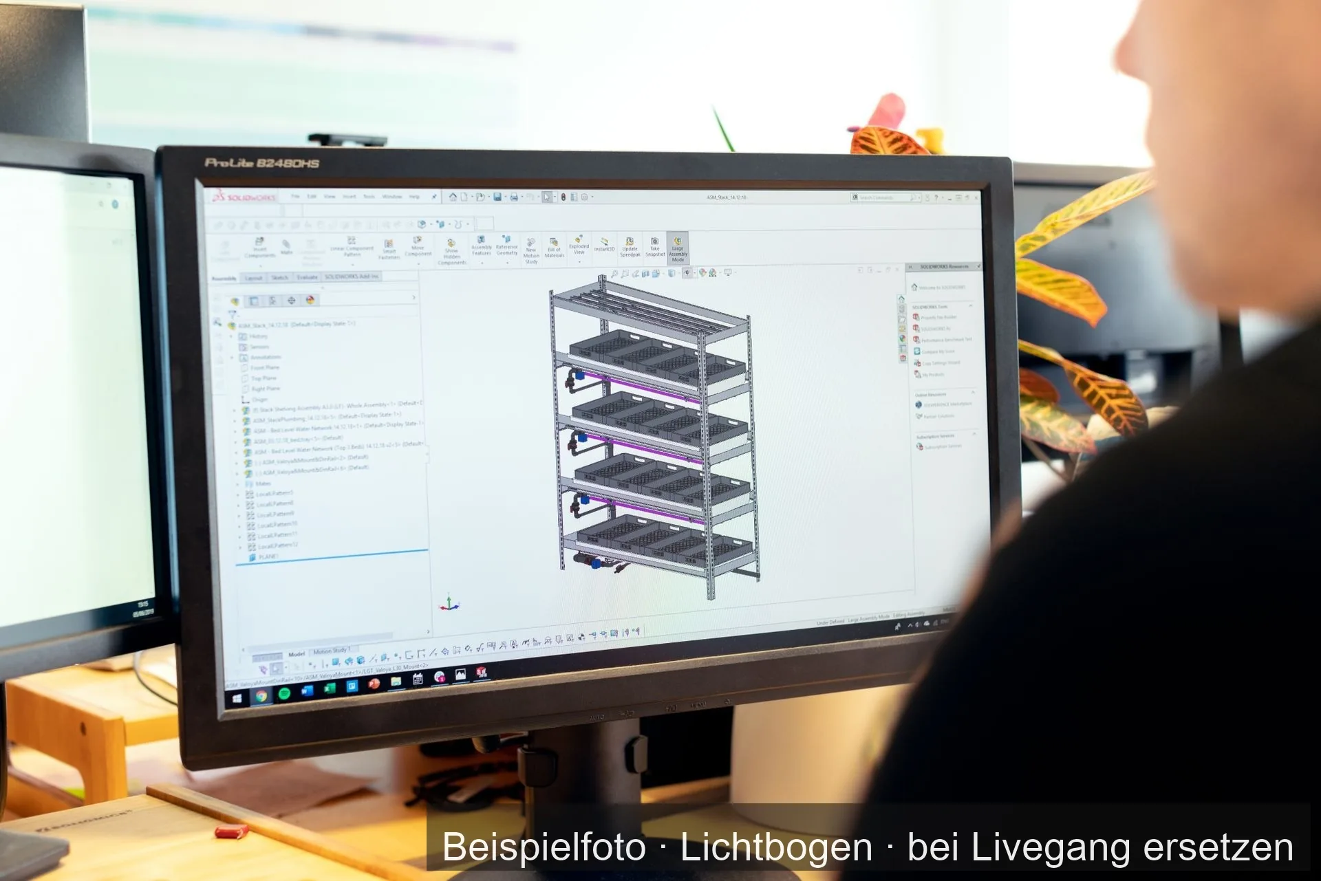 Bildschirm mit dem 3D-Modell eines Stahlregals in einem CAD-Programm, davor angeschnitten eine Person.
